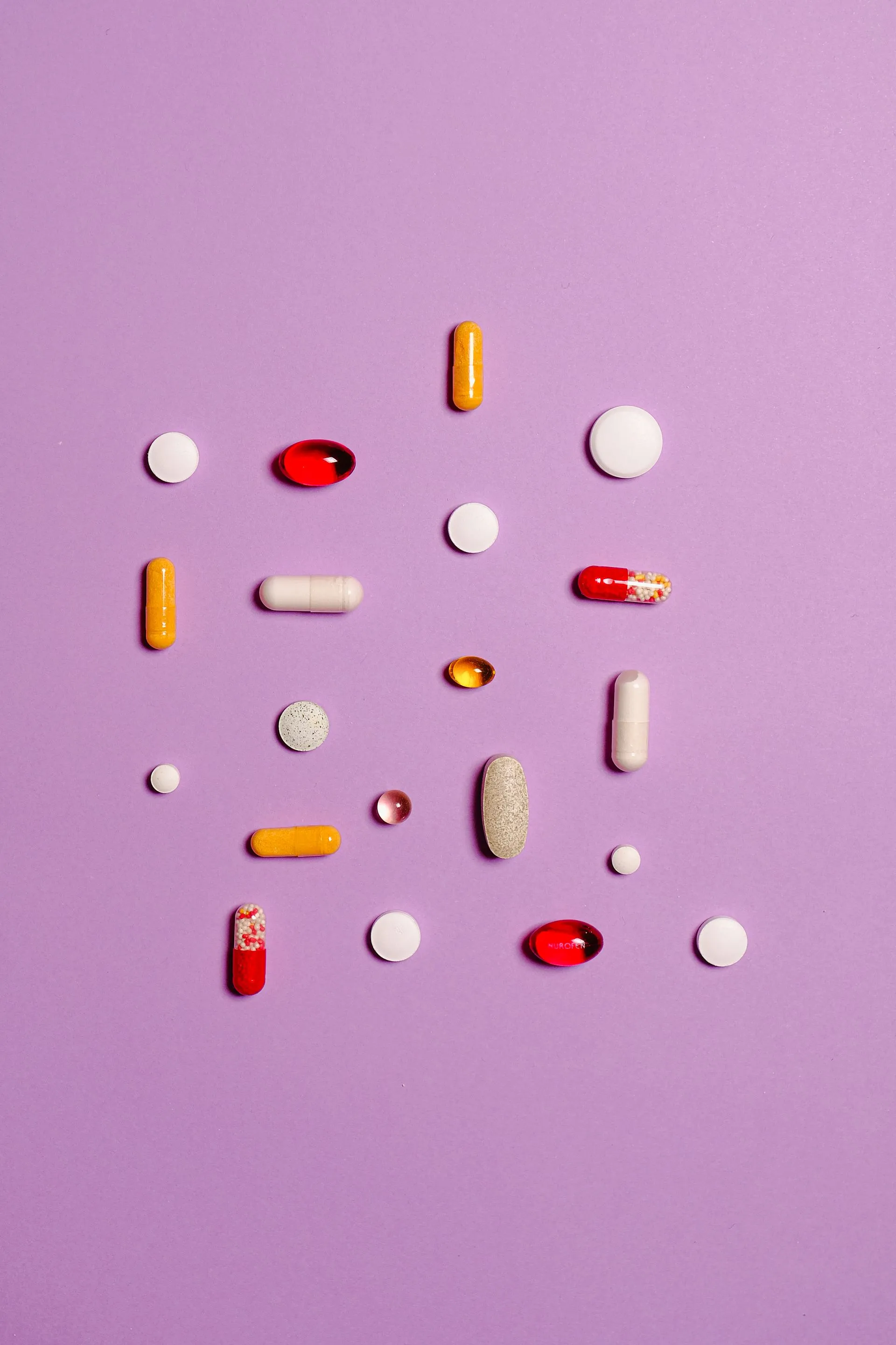 Assorted tablets and capsules laid out on a plain background